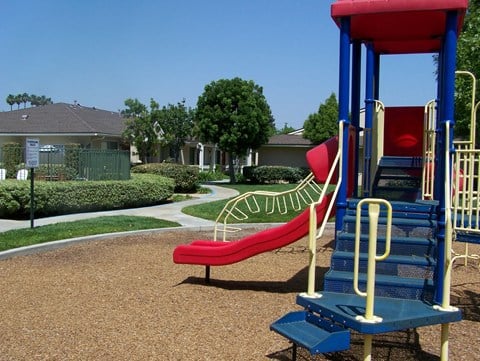 a playground with a red slide and a blue bench