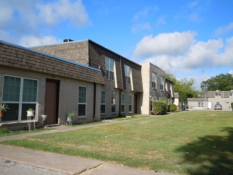an apartment building with a lawn and a blue sky