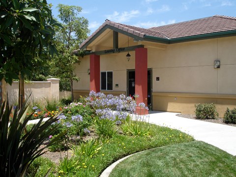 the front of a building with a sidewalk and flowers
