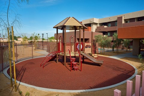 a playground at an apartment complex with a red swing set