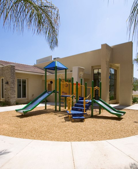 a playground in front of a house with stairs and slides