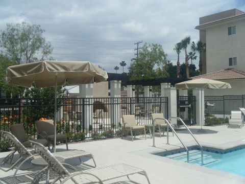 a pool with chairs and umbrellas next to a building