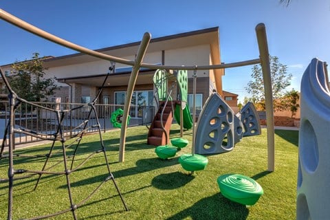 a playground with a swing set and other toys in front of a house