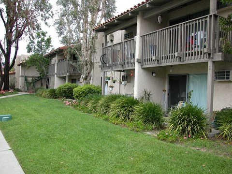 the outside of an apartment building with a lawn and a garden