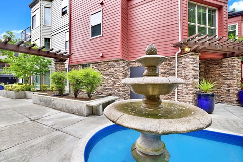 A fountain in the middle of a pool surrounded by a house.