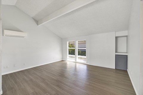 A spacious room with wooden flooring and a large window.