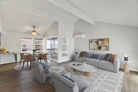 A modern living room with a grey sofa, a coffee table, and a dining table set up.