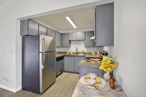 A modern kitchen with a stainless steel refrigerator and a table set for two.