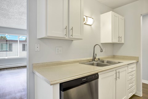 A kitchen with white cabinets and a beige countertop.