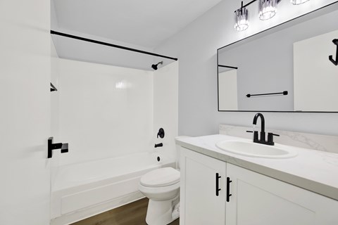 A white bathroom with a toilet, sink, and mirror.