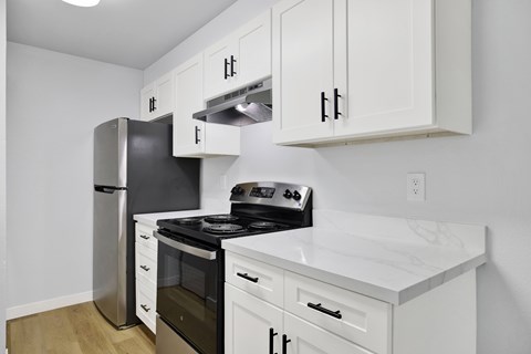 A kitchen with white cabinets and a black refrigerator.