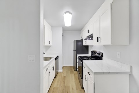 A kitchen with white cabinets and a black stove top.