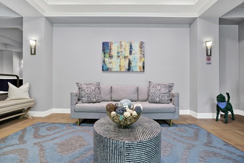 A living room with a grey couch, a coffee table, and a painting on the wall.