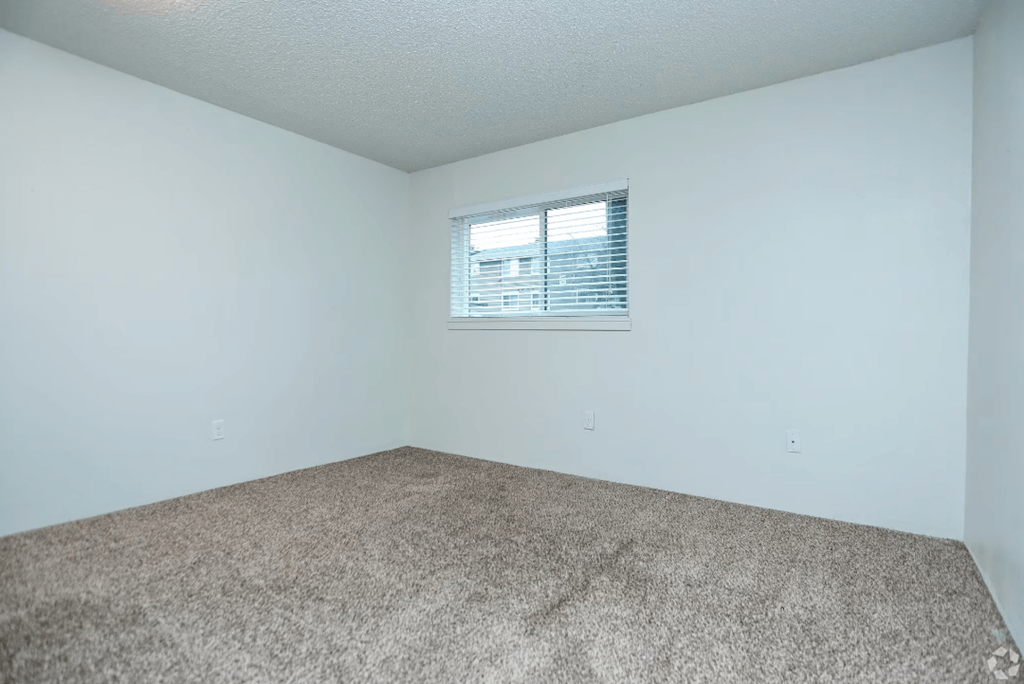 the living room of an empty room with carpet and a window at Sunset Park Apartments, Washington