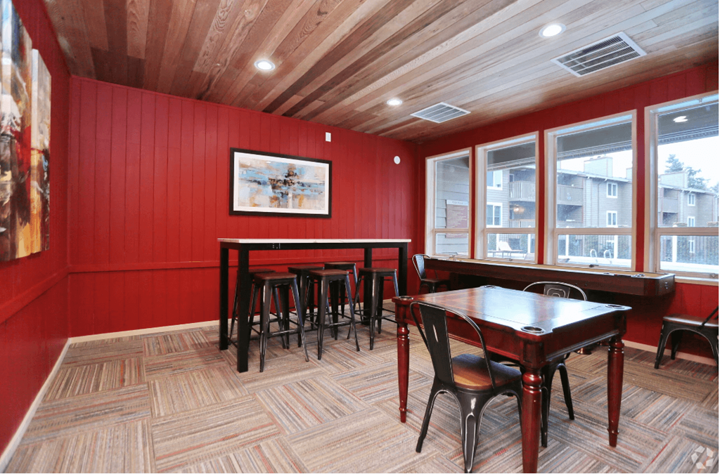 a dining room with red walls and wooden tables and chairs
