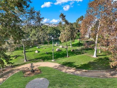 A park with a playground and a green lawn.