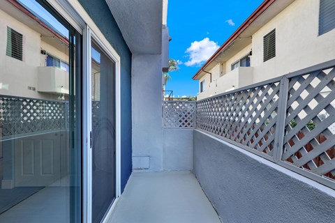 A balcony with a lattice fence and a glass door leading to a building.
