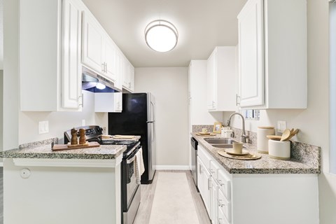A kitchen with white cabinets and granite countertops.
