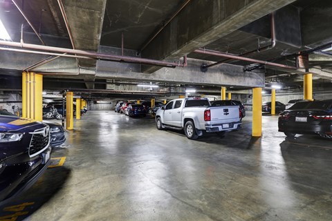 A parking garage with cars parked in yellow-painted spaces.