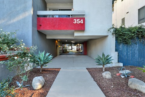 A red and white sign with the number 354 on it is mounted on a grey building.