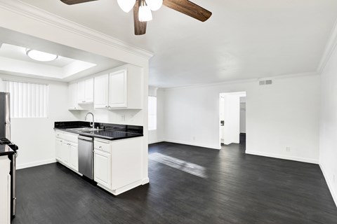 A spacious kitchen with white cabinets and black countertops.