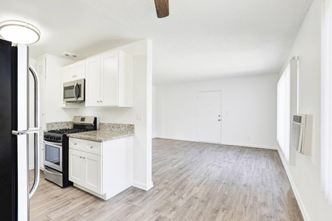 A kitchen with white cabinets and a black refrigerator.