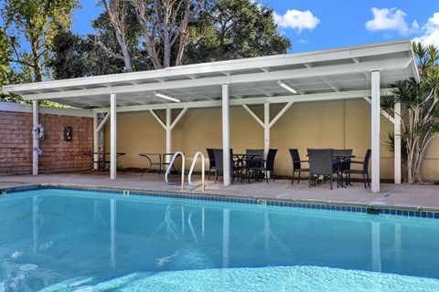A pool under a white roof with chairs and tables around it at Sylvan Gardens,California,91401