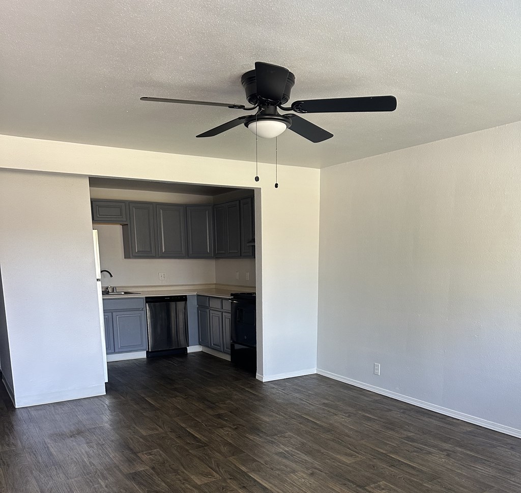 A room with a ceiling fan and wooden flooring.