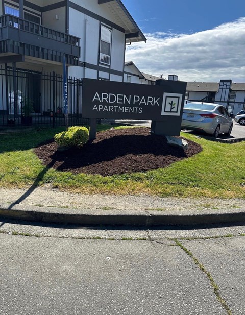 A sign for Arden Park Apartments is in front of a building.