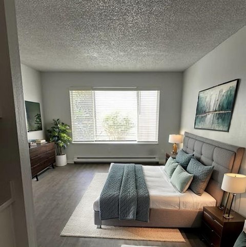 A bedroom with a large bed and a window with blinds.