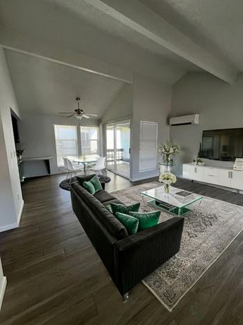 A living room with a black couch and a glass coffee table.