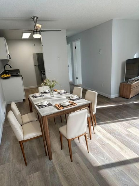 A dining room with a table set for two and a television in the background.