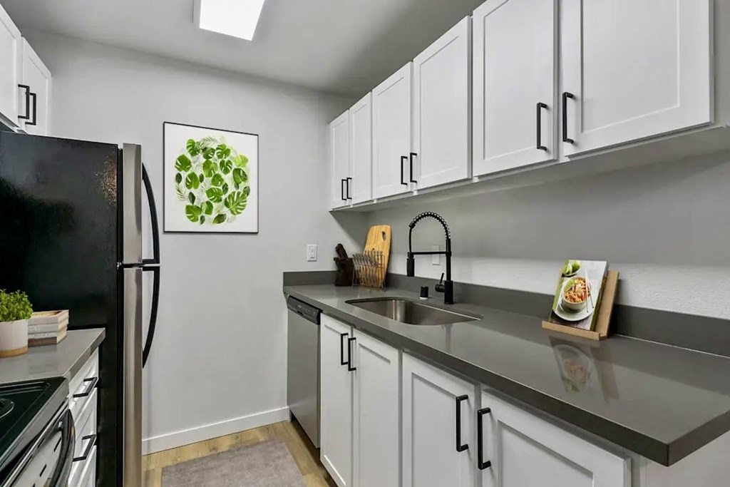 Kitchen with a black refrigerator and white cabinets at Capri Apartments, Mountlake Terrace, Washington