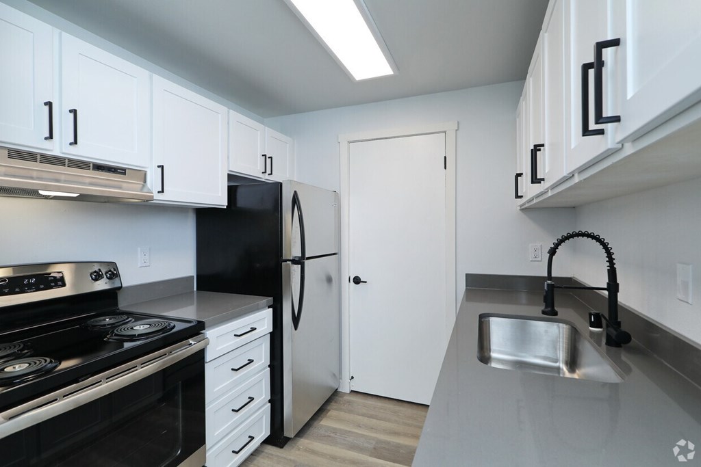 Kitchen with black appliances and white cabinets at Capri Apartments, Mountlake Terrace