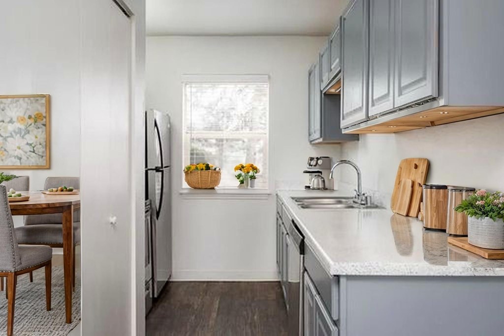 A kitchen with a refrigerator, sink, and a dining table with chairs.