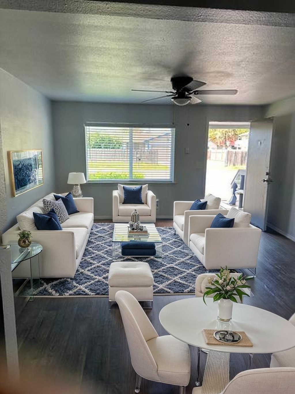 A living room with white furniture and a ceiling fan.