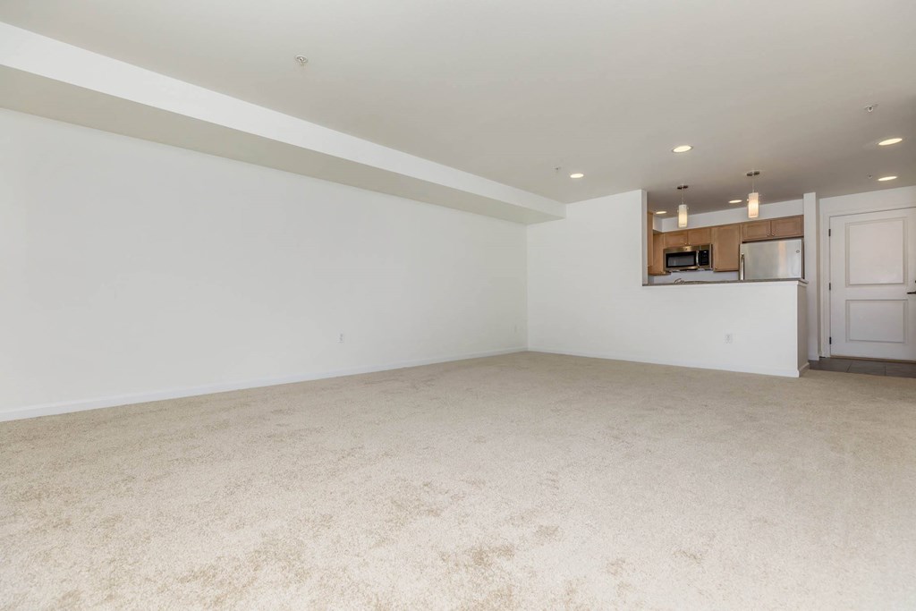 an empty living room and kitchen with white walls and carpet  at Delano, Redmond, WA