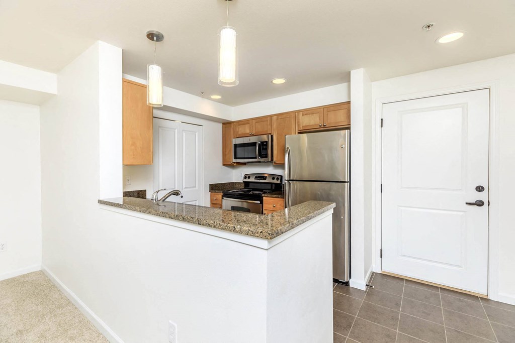 a kitchen with a granite counter top and a stainless steel refrigerator  at Delano, Redmond, 98052
