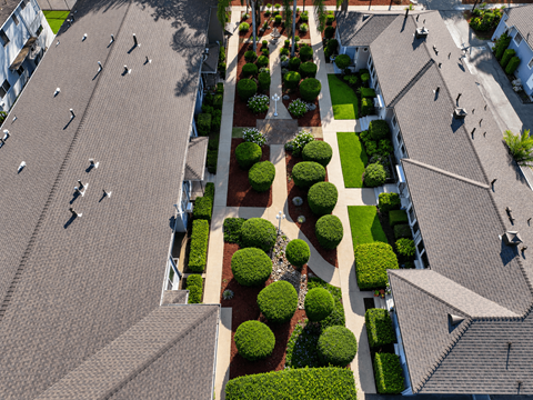 A bird's eye view of a residential area with houses and well-manicured gardens.