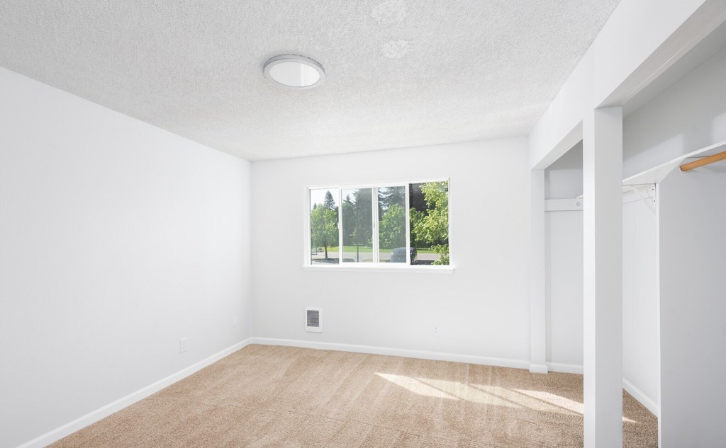 A room with a window and a wooden floor.