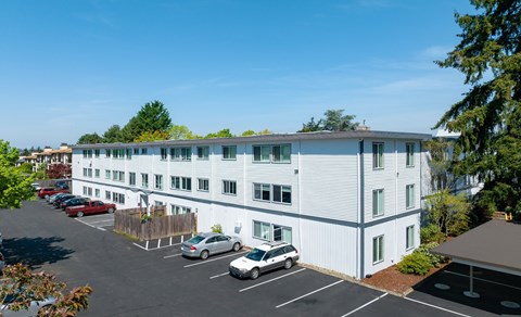 A white building with a parking lot in front of it.