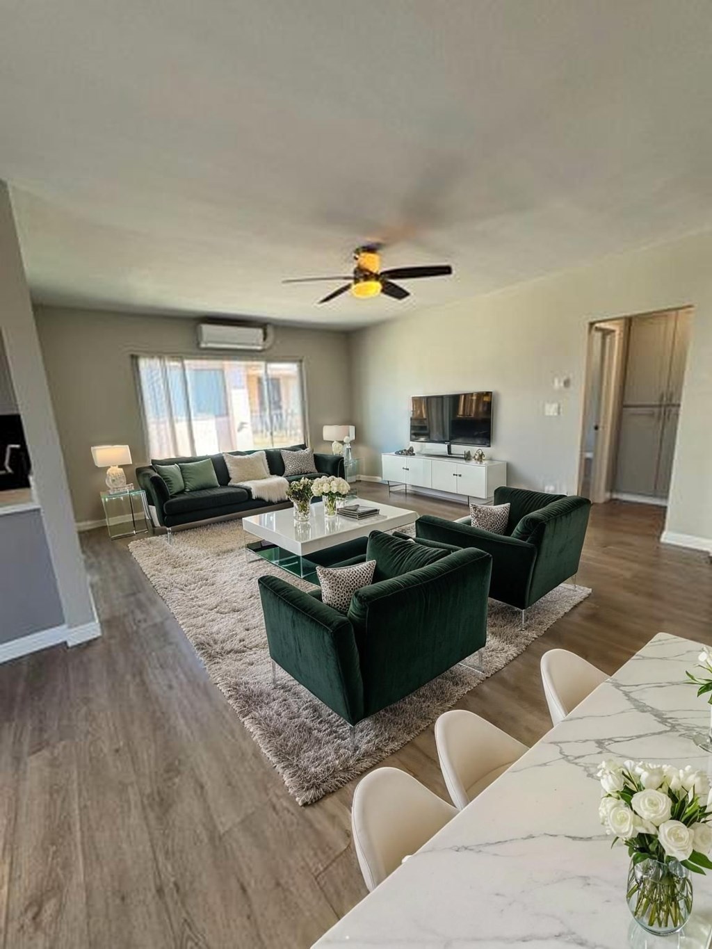 A living room with a green couch and a white dining table.