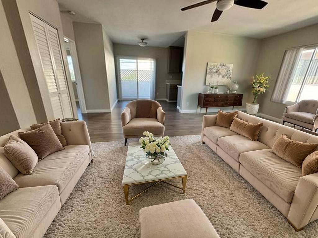 A living room with a large beige sofa, a coffee table, and a ceiling fan.