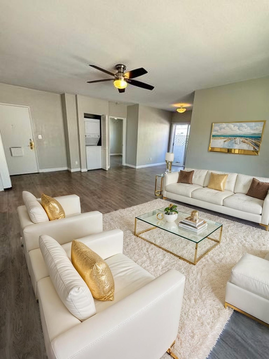 A living room with white furniture and a ceiling fan.