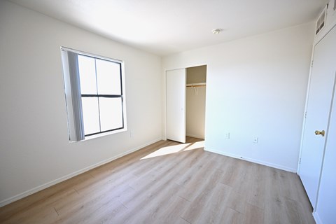A room with a window and a door is empty and waiting to be furnished.