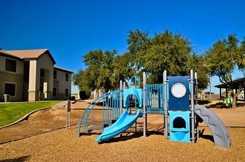 A playground with a blue slide and a green slide.