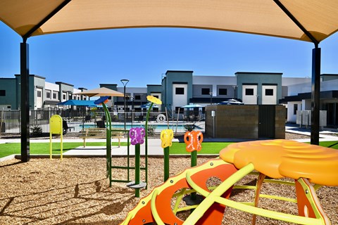 A playground with a yellow slide and a green climbing frame.