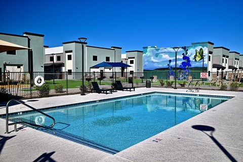 A swimming pool in front of a building with a mural on the wall.