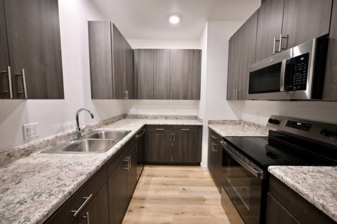 A modern kitchen with dark wood cabinets and granite countertops.