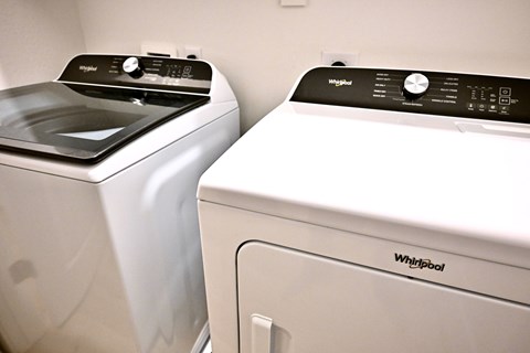 Two white Whirlpool washing machines side by side.